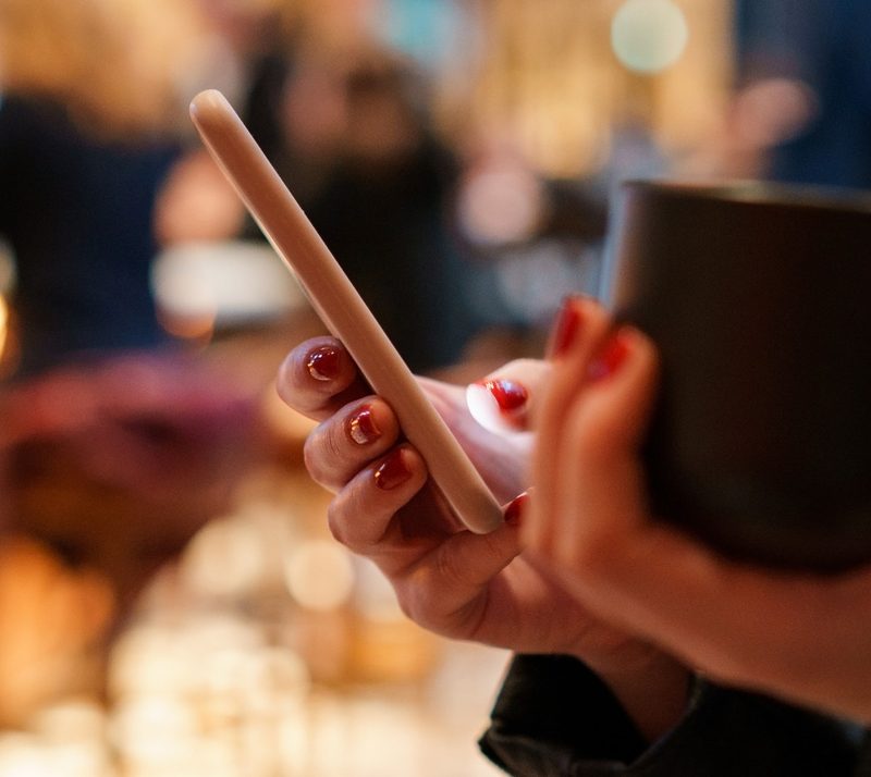 A customer checking her phone at a busy bar