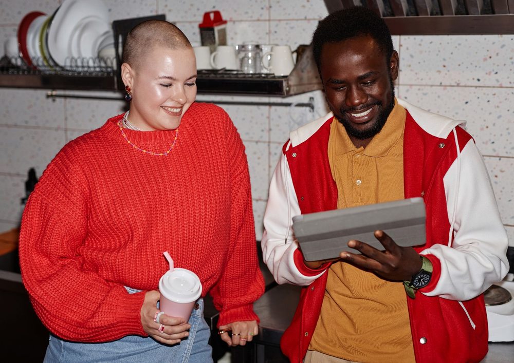 Two venue staff smiling at a tablet in the kitchen