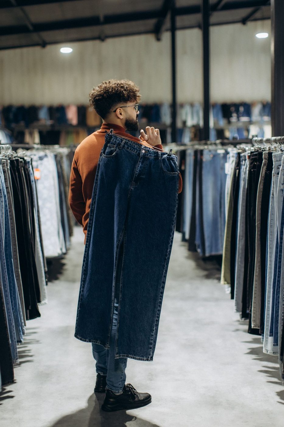 A man holding up a pair of jeans in a denim store