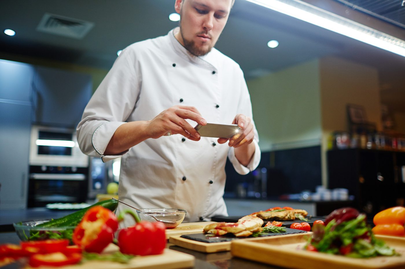 A chef photographs his plated dish in the kitchen