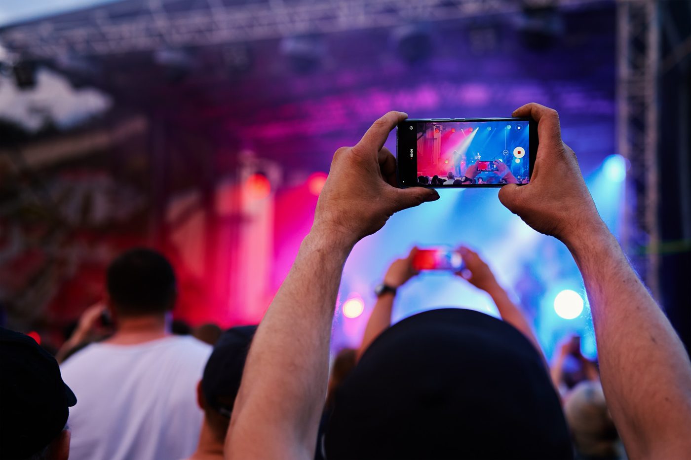 A fan films the band on stage from the crowd