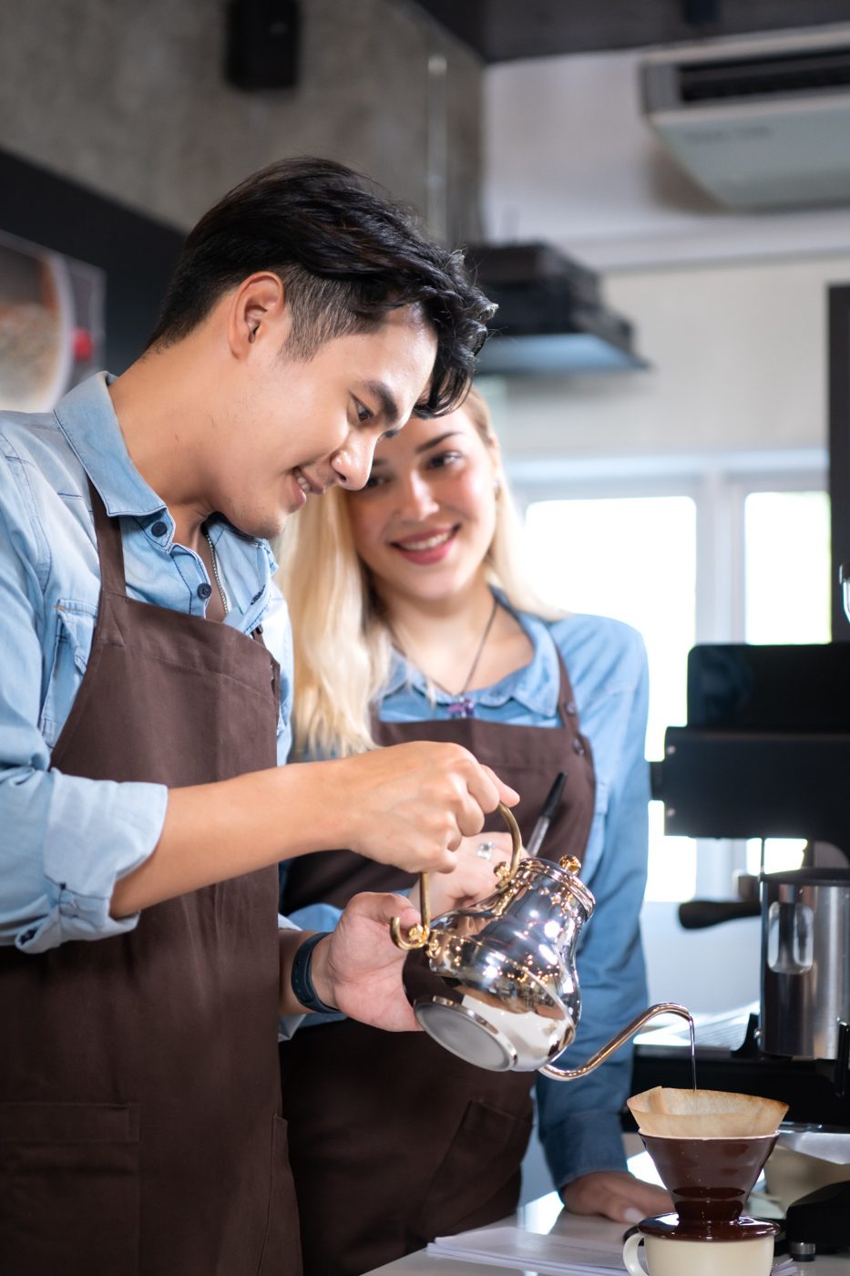 A barista shows a colleague a pour-over coffee
