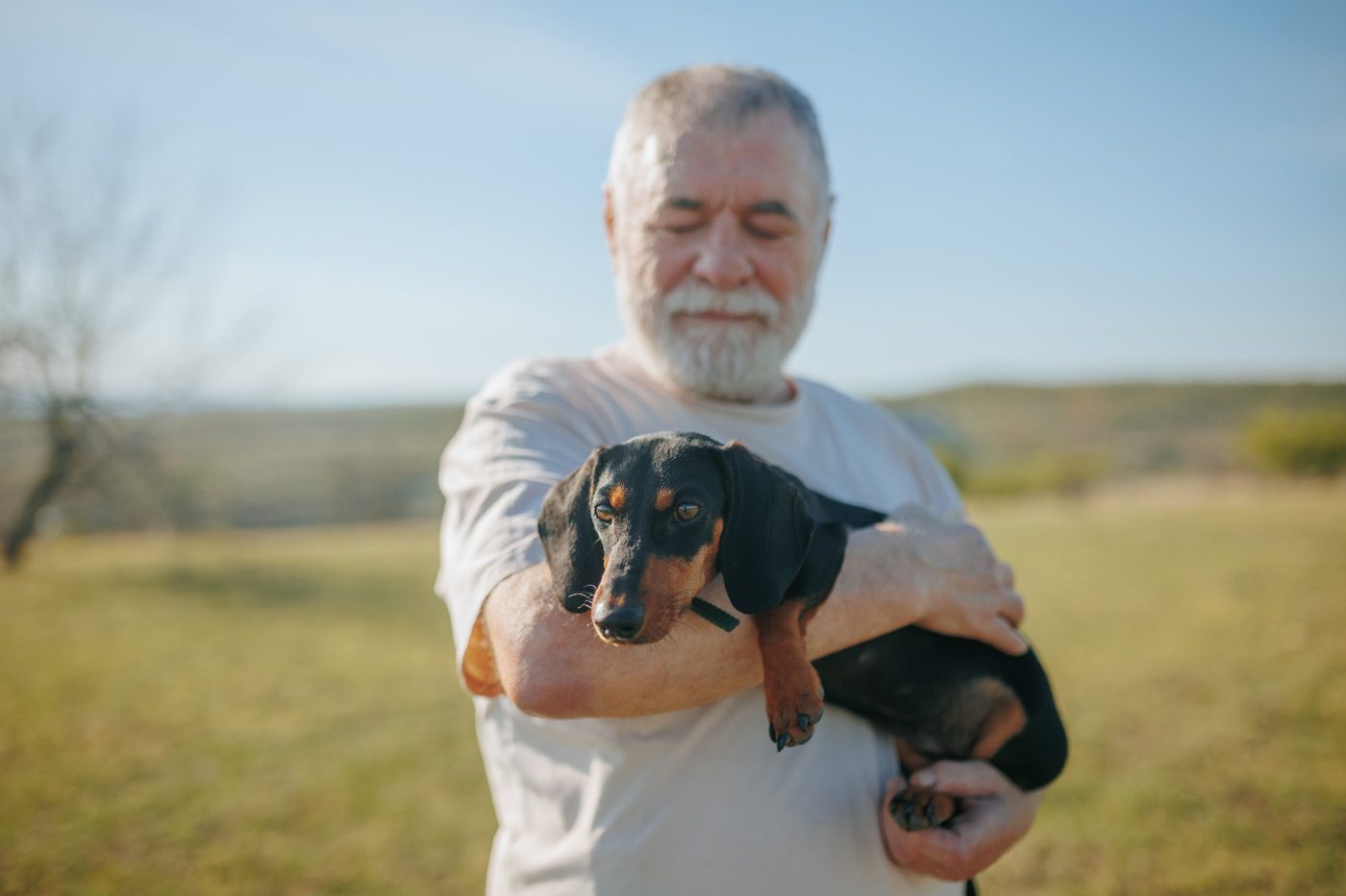 A man holding his dachshund out on a walk