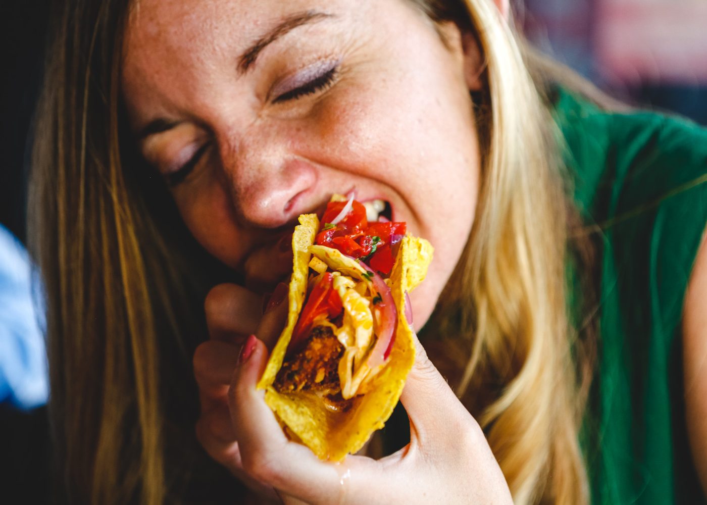 A woman taking a big bite of a taco at the cantina