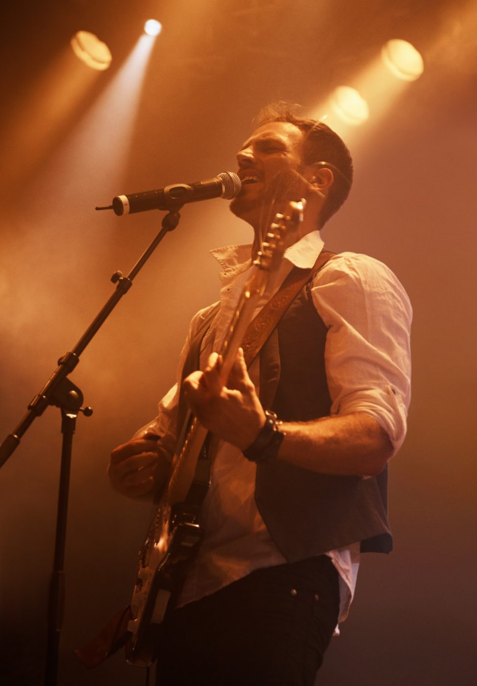 A singer and guitarist performing under stage lights