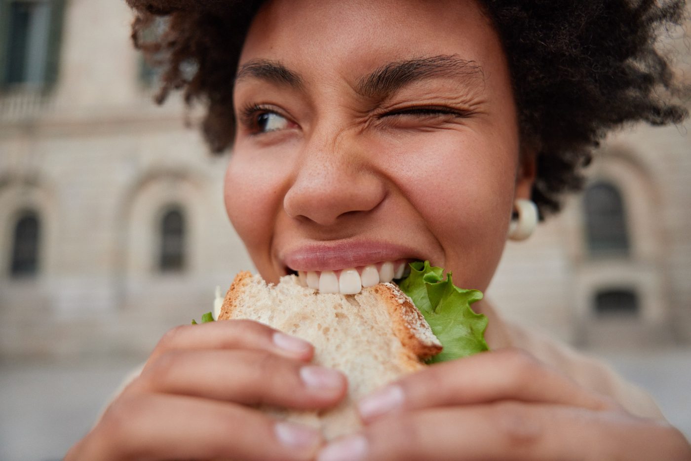 A woman taking a big bite of her sandwich