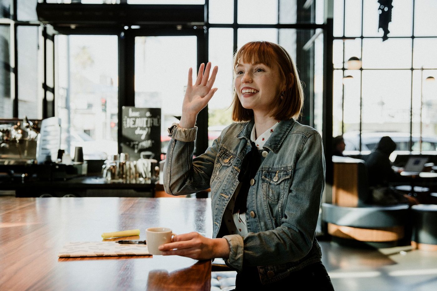 A smiling customer waving from her table at the cafe