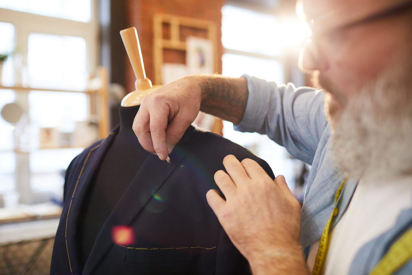 A tailor chalking the fit on a jacket in the workshop