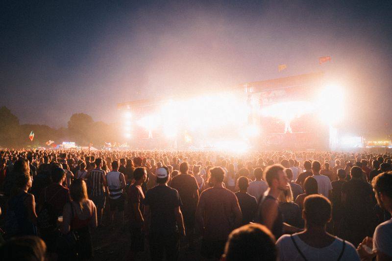 A crowd faces a lit stage at a night-time festival