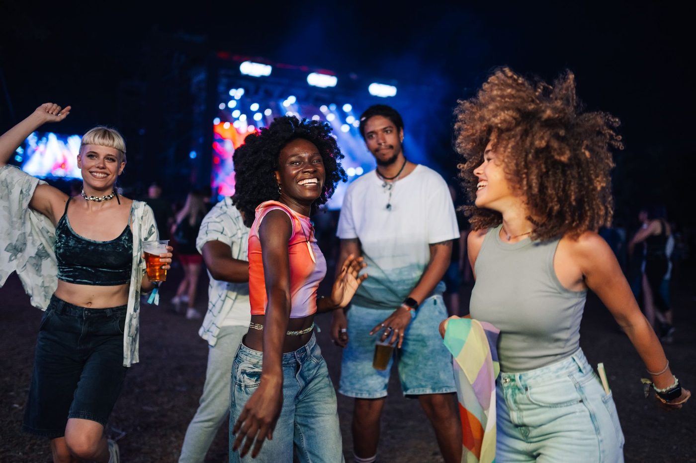 Friends dance together at a night-time music festival