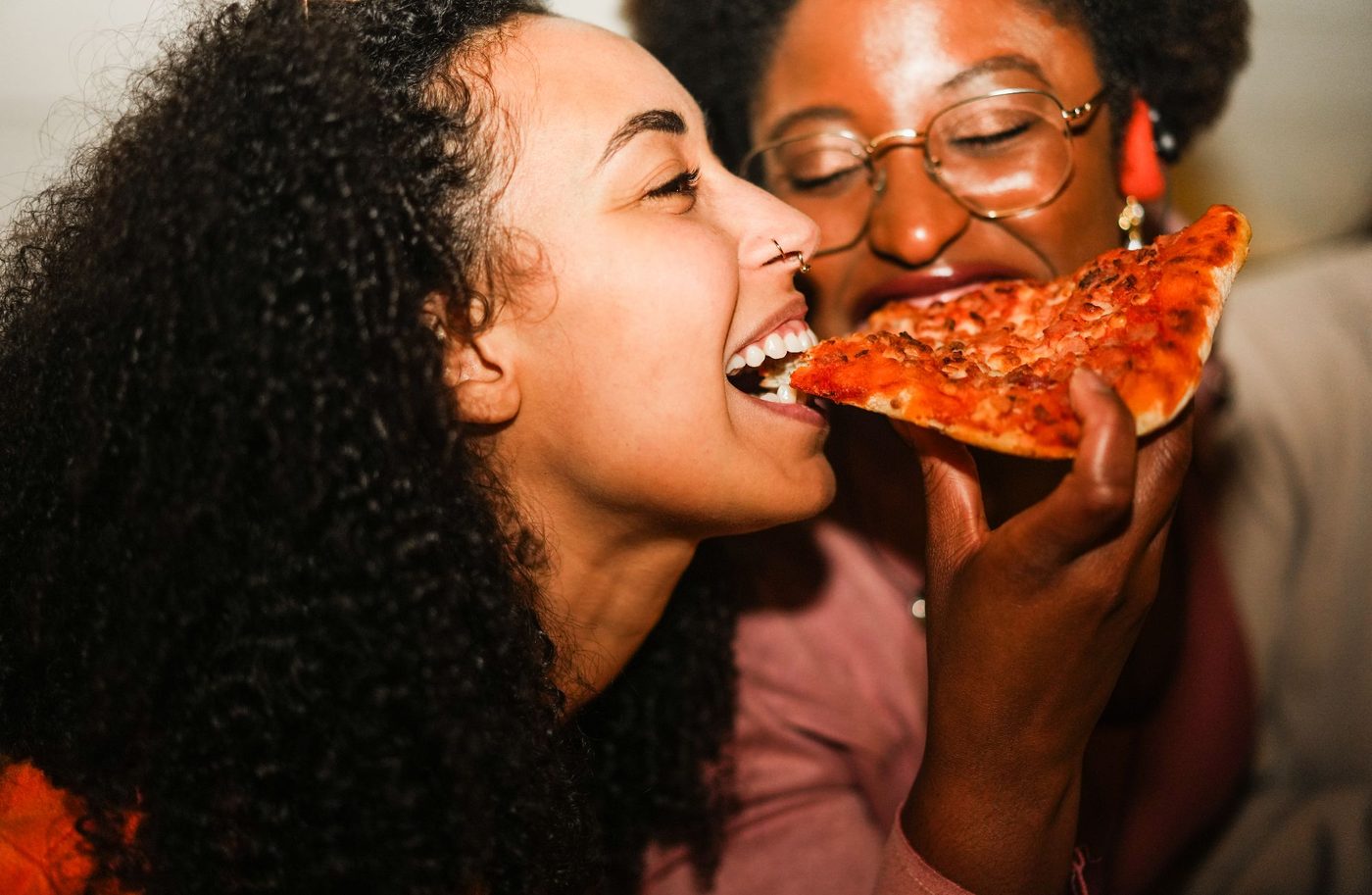 Two friends share a slice of pizza