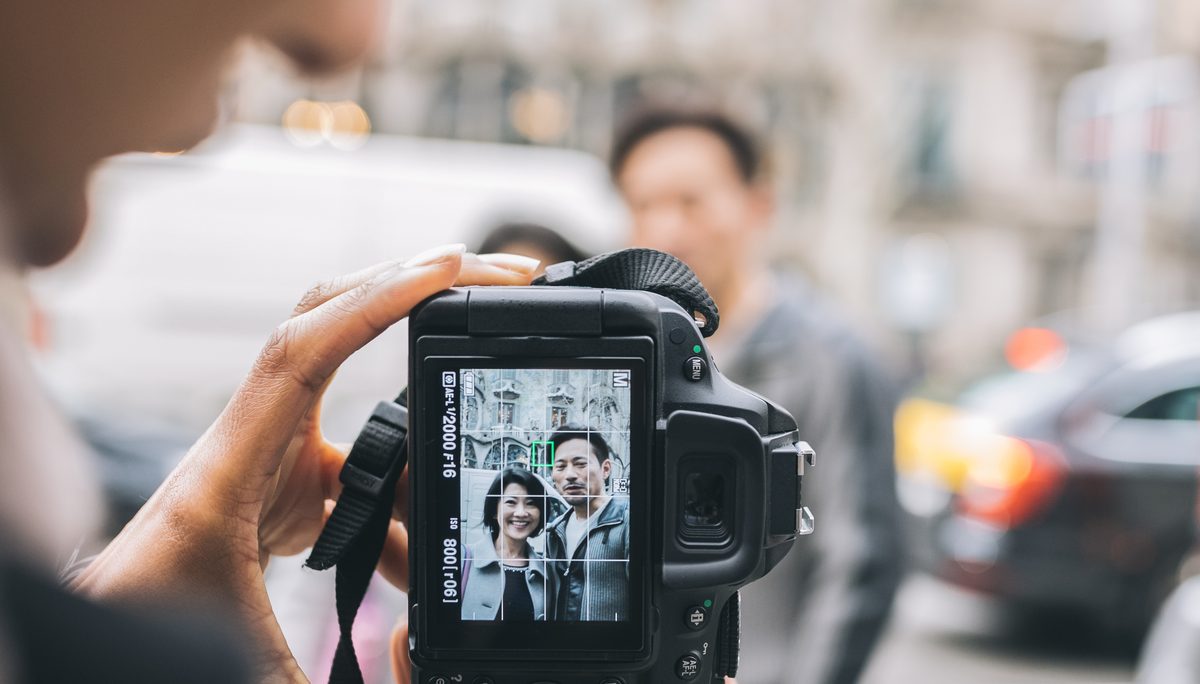 A photographer framing a couple on the camera screen in the street
