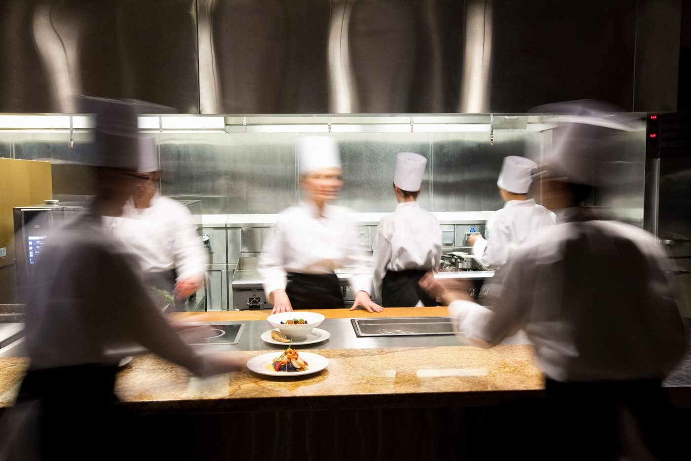 Chefs at work on the pass of a busy restaurant kitchen