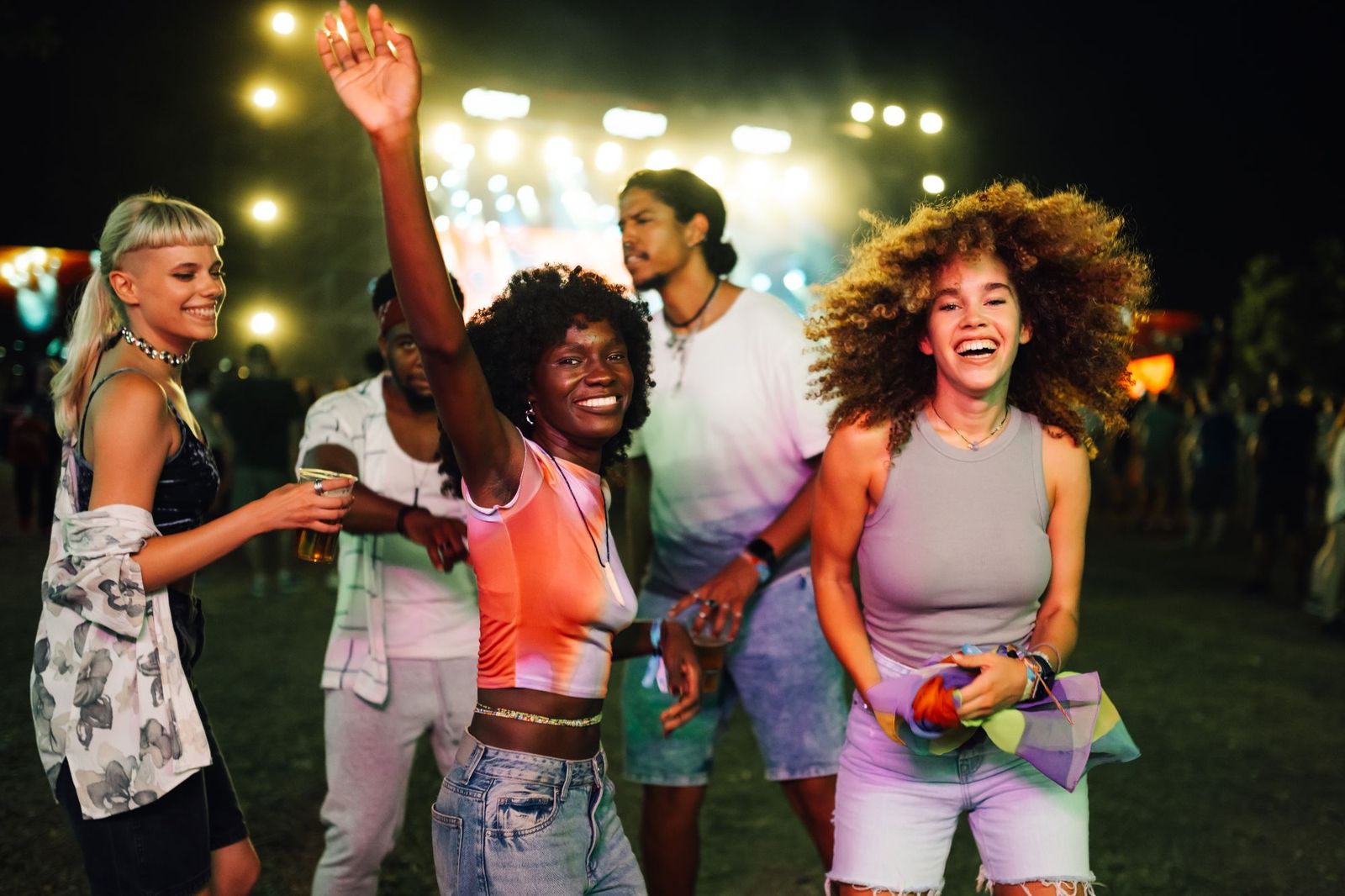 Friends dancing and laughing together at a night-time festival